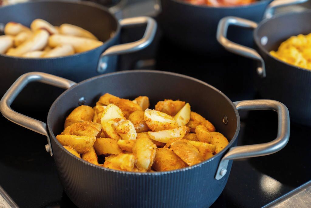 A close-up of a cooking pan with golden-brown potato wedges.