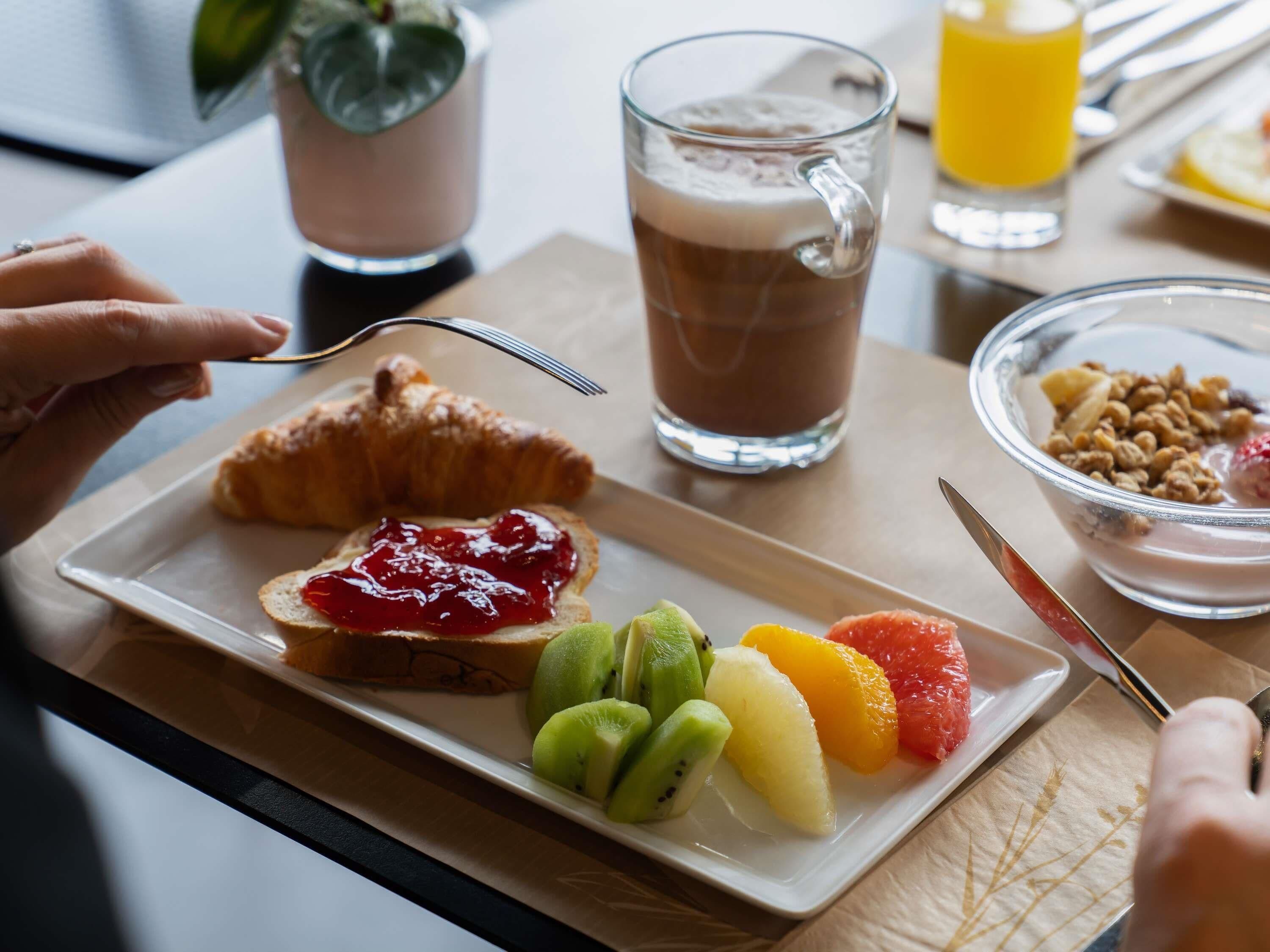 A breakfast setting with croissant, fruit, and a beverage.