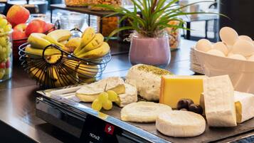 A cheese and fruit display with a sign indicating Swiss origin.