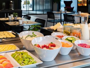 A buffet with various food items including fruits, cheeses, and a milk jug. - Novotel Suites Geneve Aeroport (Vernier)