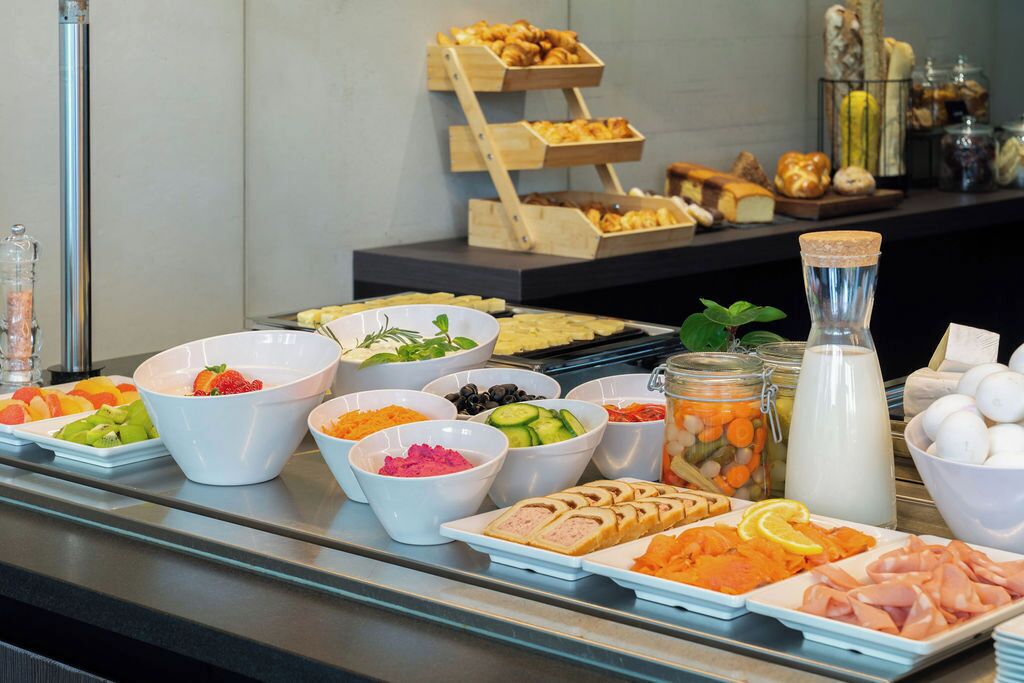 A buffet with various food items including fruits, vegetables, meats, and cheeses.