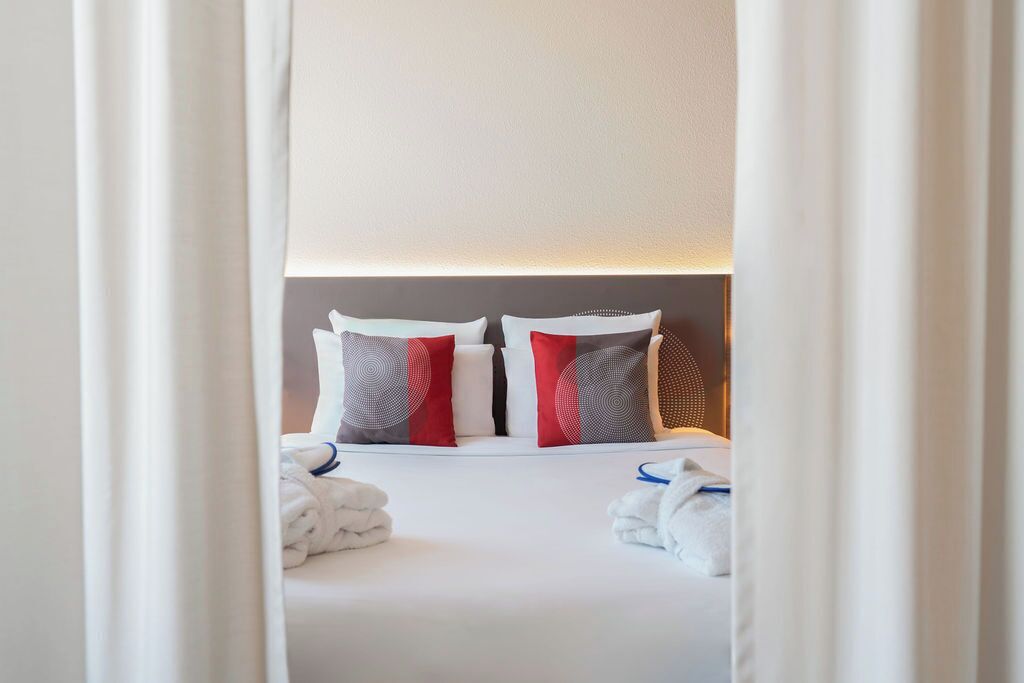 Habitación de hotel con una cama bien hecha, dos almohadas y cabecera.