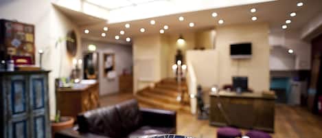A spacious living area with a high ceiling, a staircase, and a modern kitchen area.