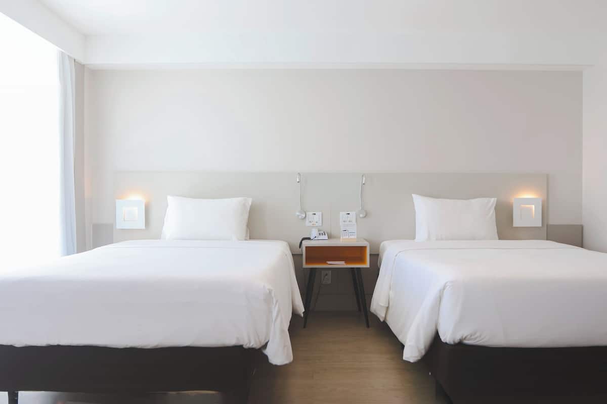 Ein Hotelzimmer mit zwei Betten, einem Nachttisch und Nachttischlampen.