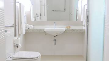 Un baño pequeño y limpio, con inodoro, lavamanos y espejo.