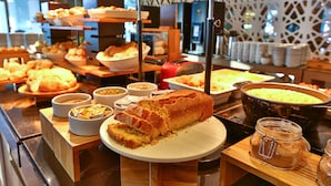 A buffet with various food items including bread, pastries, and a large pot of food. - Radisson Hotel Recife (Recife)