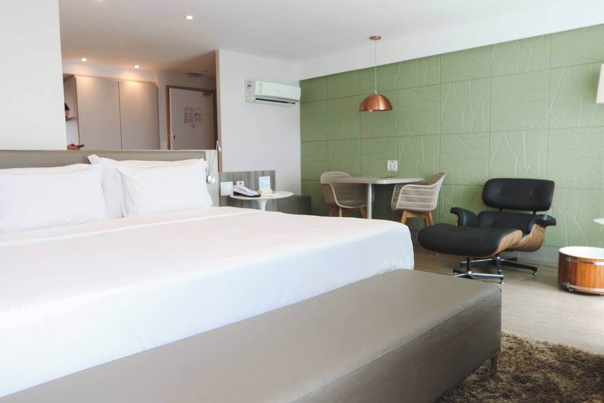 Ein modernes Hotelzimmer mit einem großen Bett, einem Schreibtisch, einem Stuhl und einem kleinen Tisch.