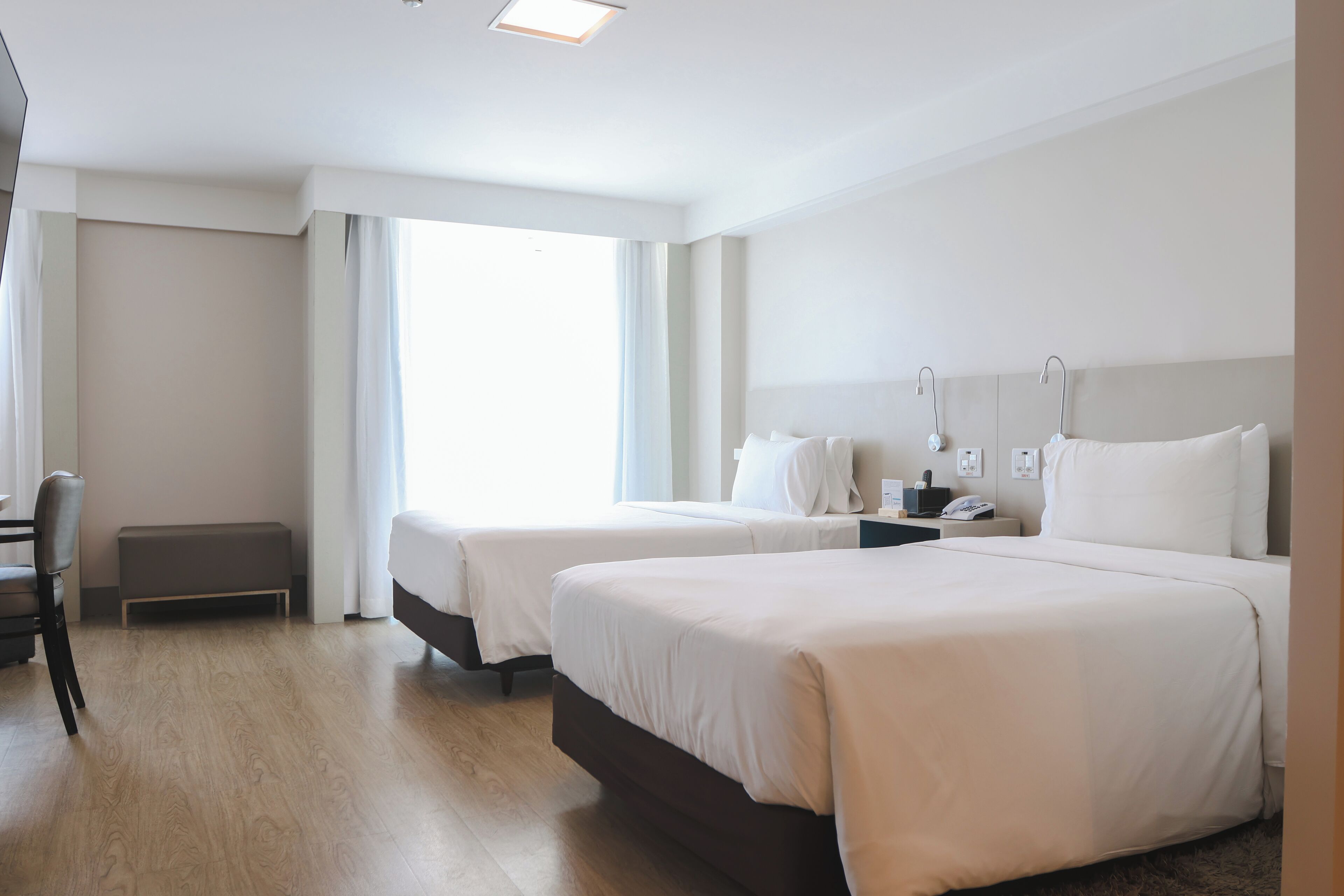 Ein Hotelzimmer mit zwei Betten, einem Schreibtisch und einem Stuhl.