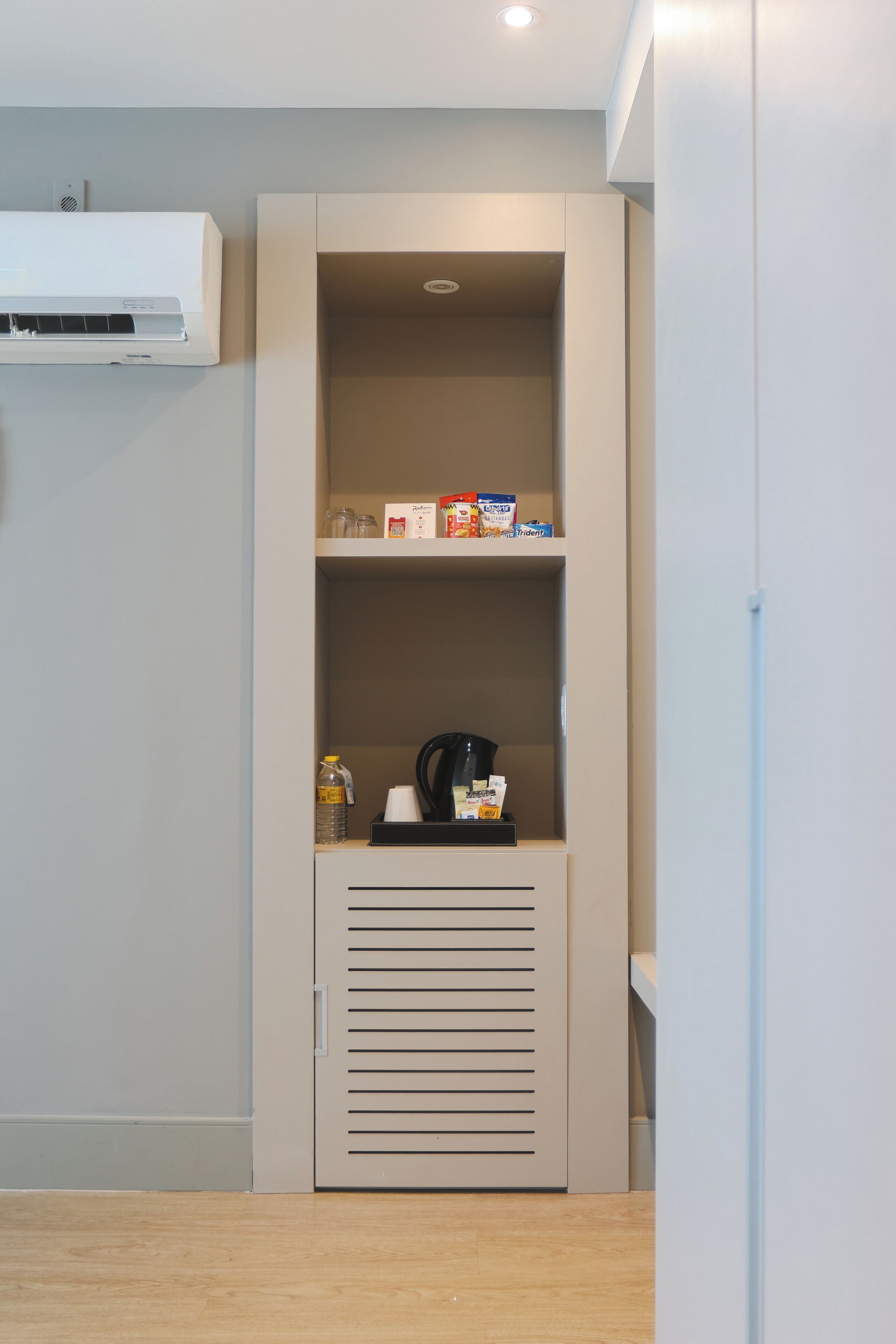 A kitchenette with a built-in oven, a coffee maker, and a water dispenser on the countertop.