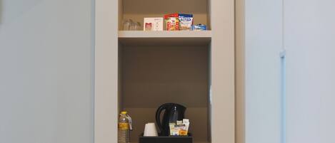 Una kitchenette con horno empotrado, cafetera y dispensador de agua sobre la encimera.