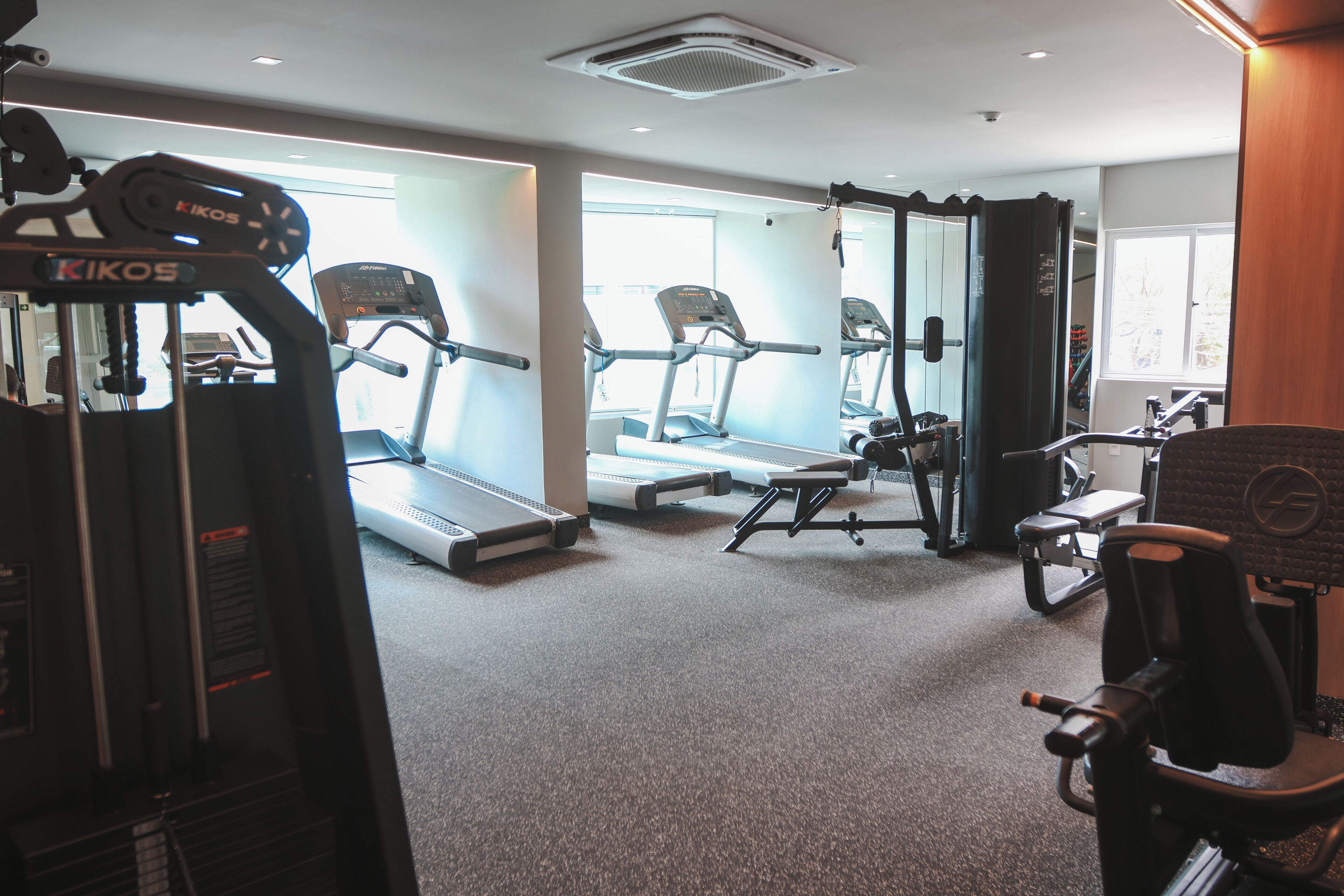 A gym with treadmills, weight machines, and a mirrored wall.