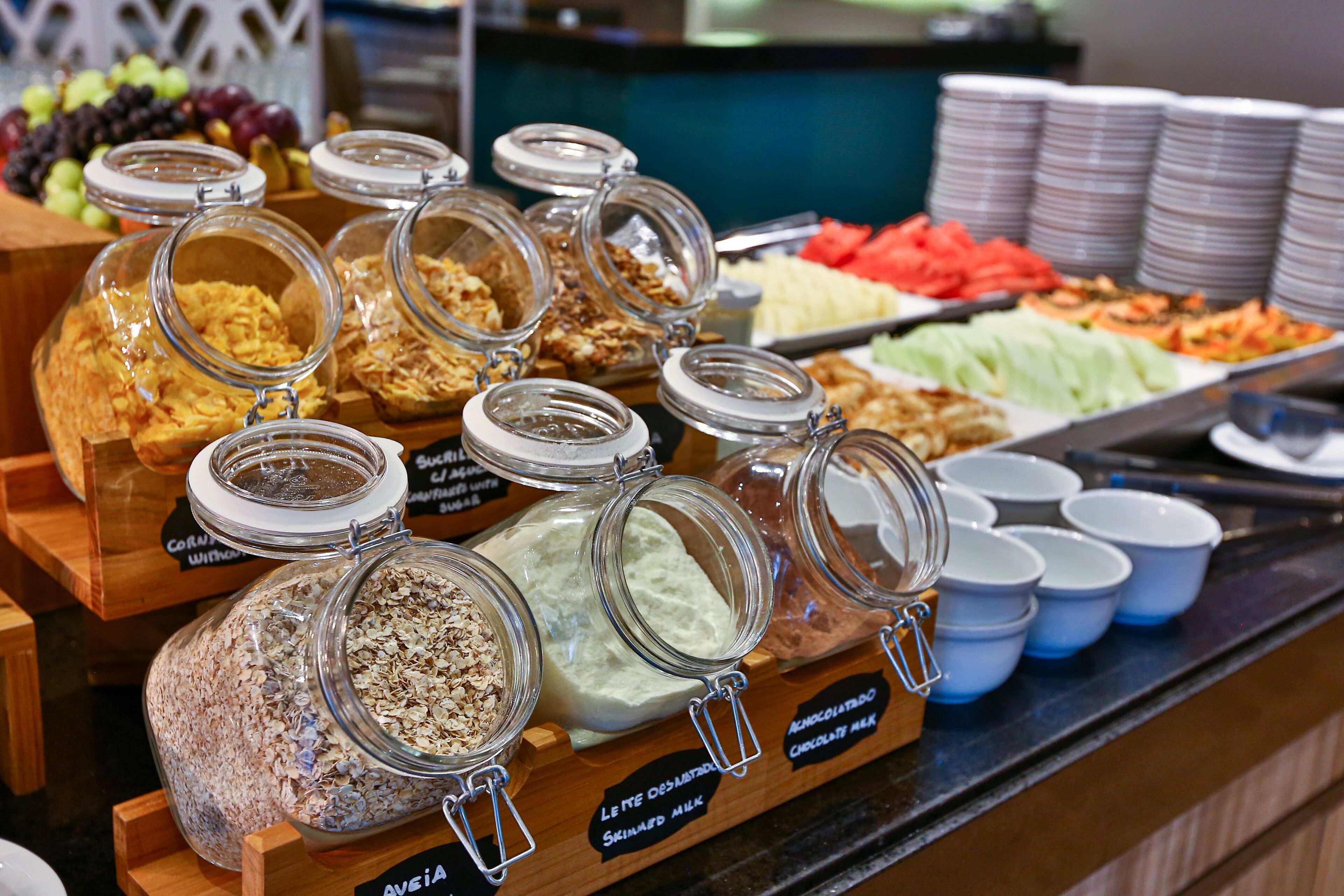 Un bufé con diversos alimentos y recipientes, incluyendo frascos de cereal y leche.