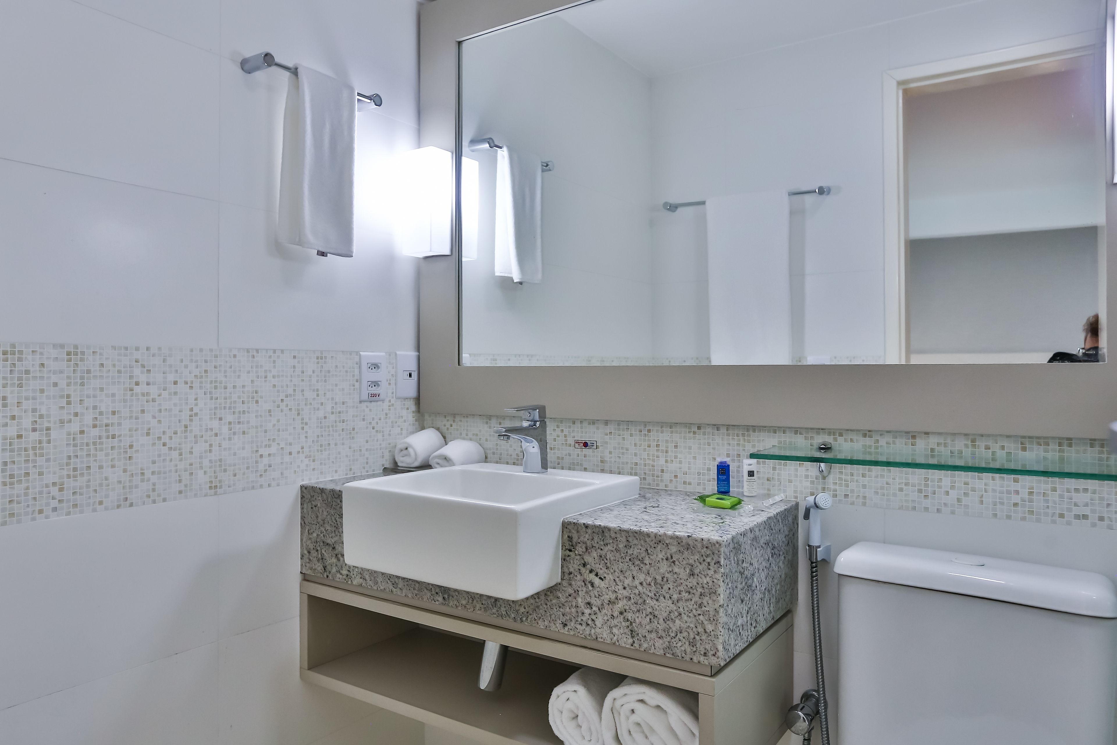 A bathroom with a white sink, a glass shower enclosure, and a mirror above the sink.