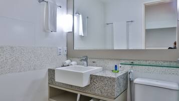 A bathroom with a white sink, a glass shower enclosure, and a mirror above the sink.