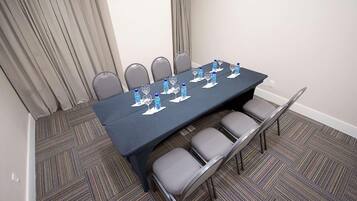A conference room with a long table, grey chairs, water bottles, and glasses.