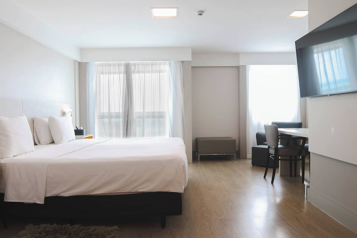 Ein modernes Hotelzimmer mit einem großen Bett, einem Schreibtisch und einem Fernseher.