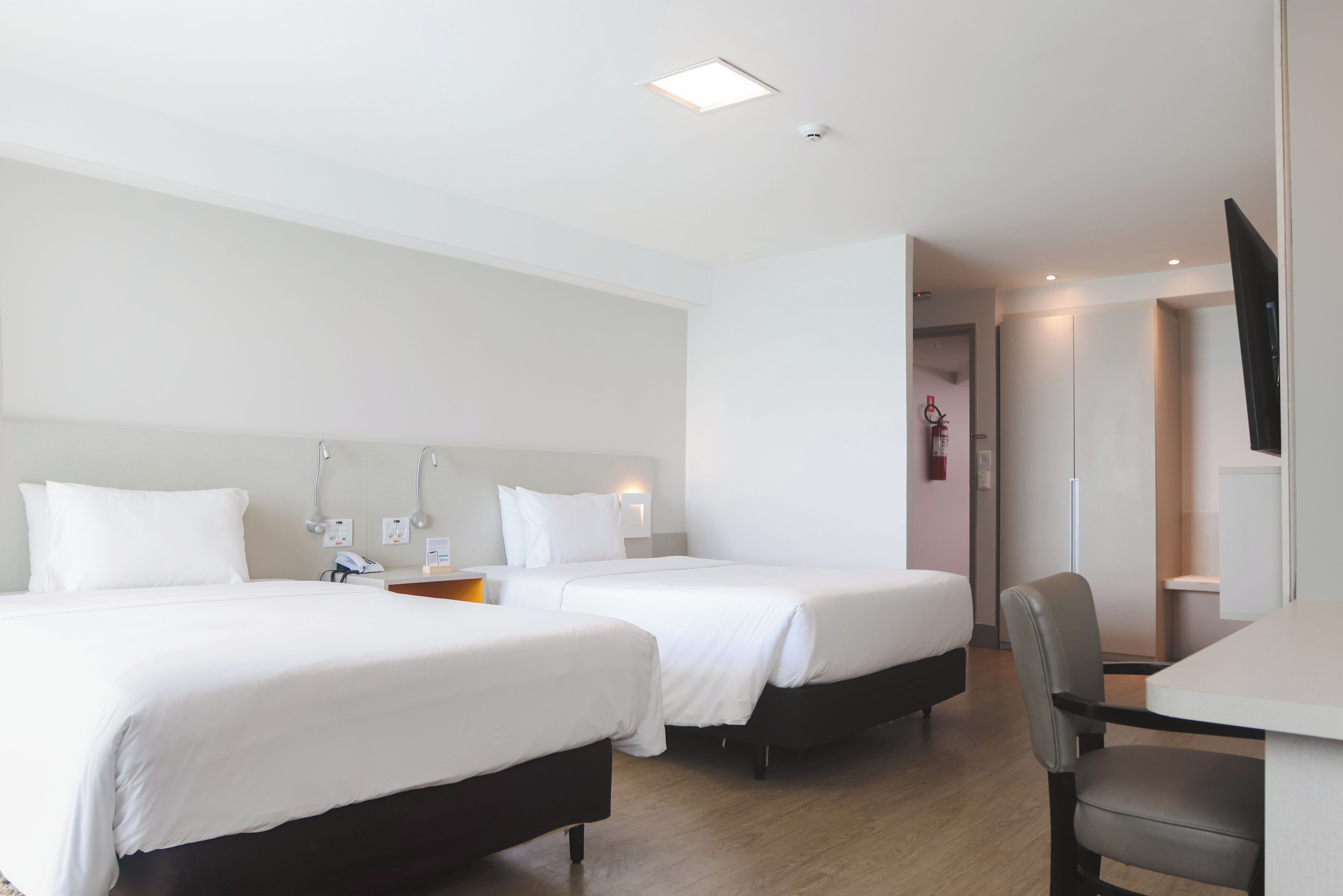 Habitación de hotel con dos camas, un escritorio y una televisión.