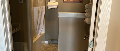 A bathroom with a shower, a towel rack, a painting, and a toilet.