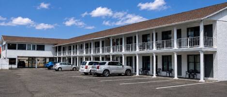 A motel with a two-story structure, a covered parking area, and a clear sky.