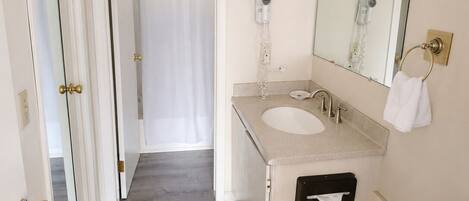 Un baño con lavabo, espejo, toallero y secador de pelo.