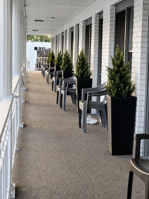 A covered outdoor seating area with rows of chairs and potted plants. - Continental Inn (Cheboygan)
