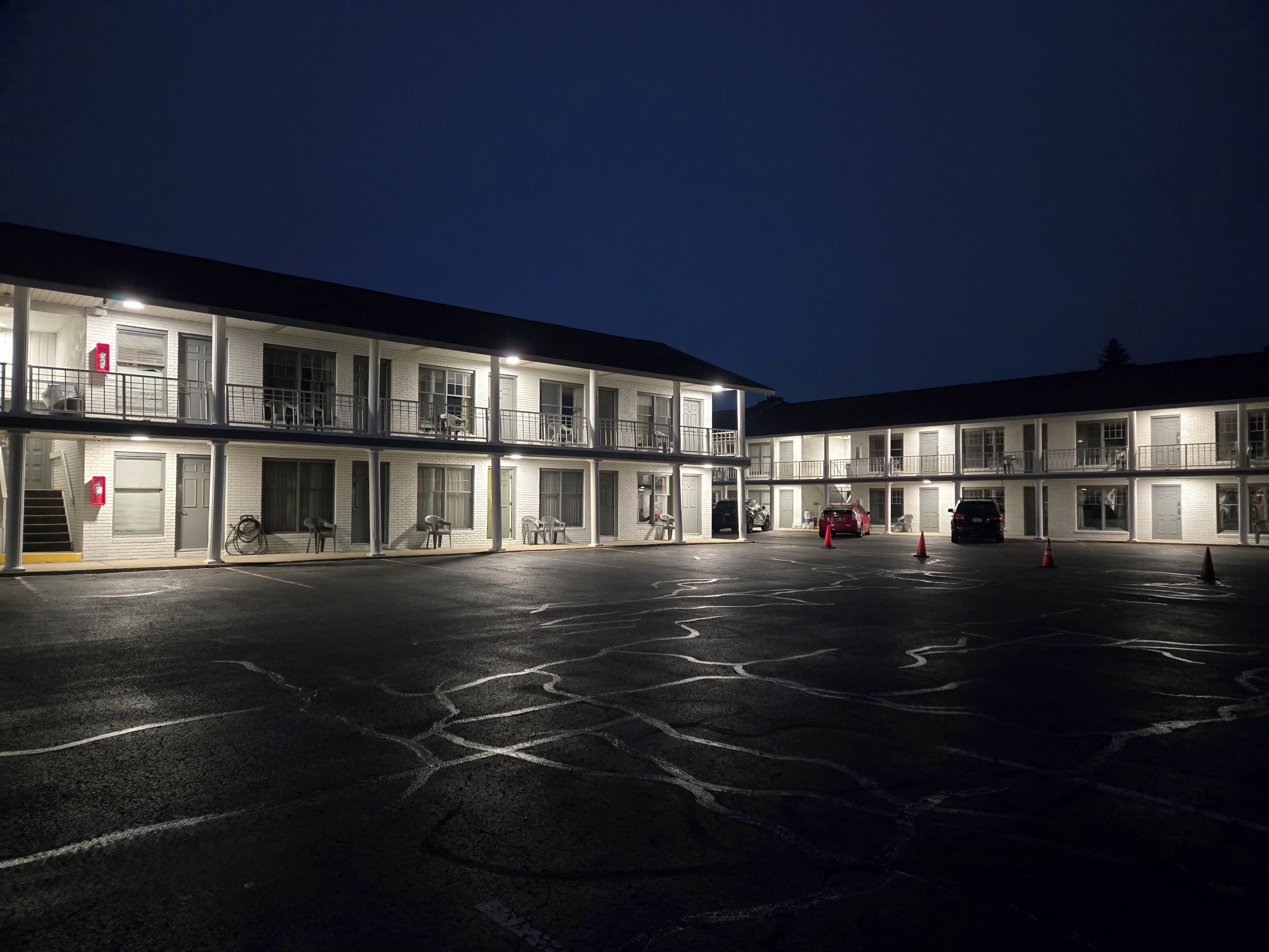 A multi-story motel with a parking lot at night.