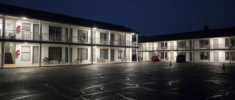 A multi-story motel with a parking lot at night.