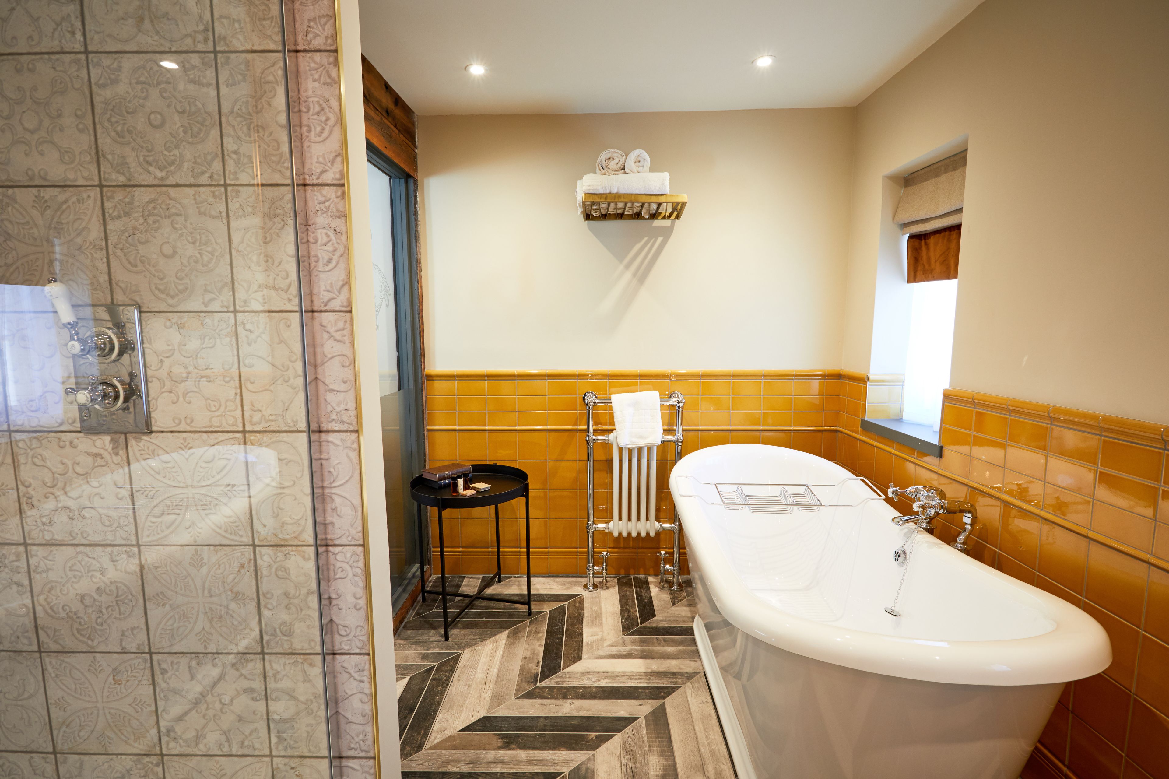 A bathroom with a bathtub, a towel rack, and a small table.