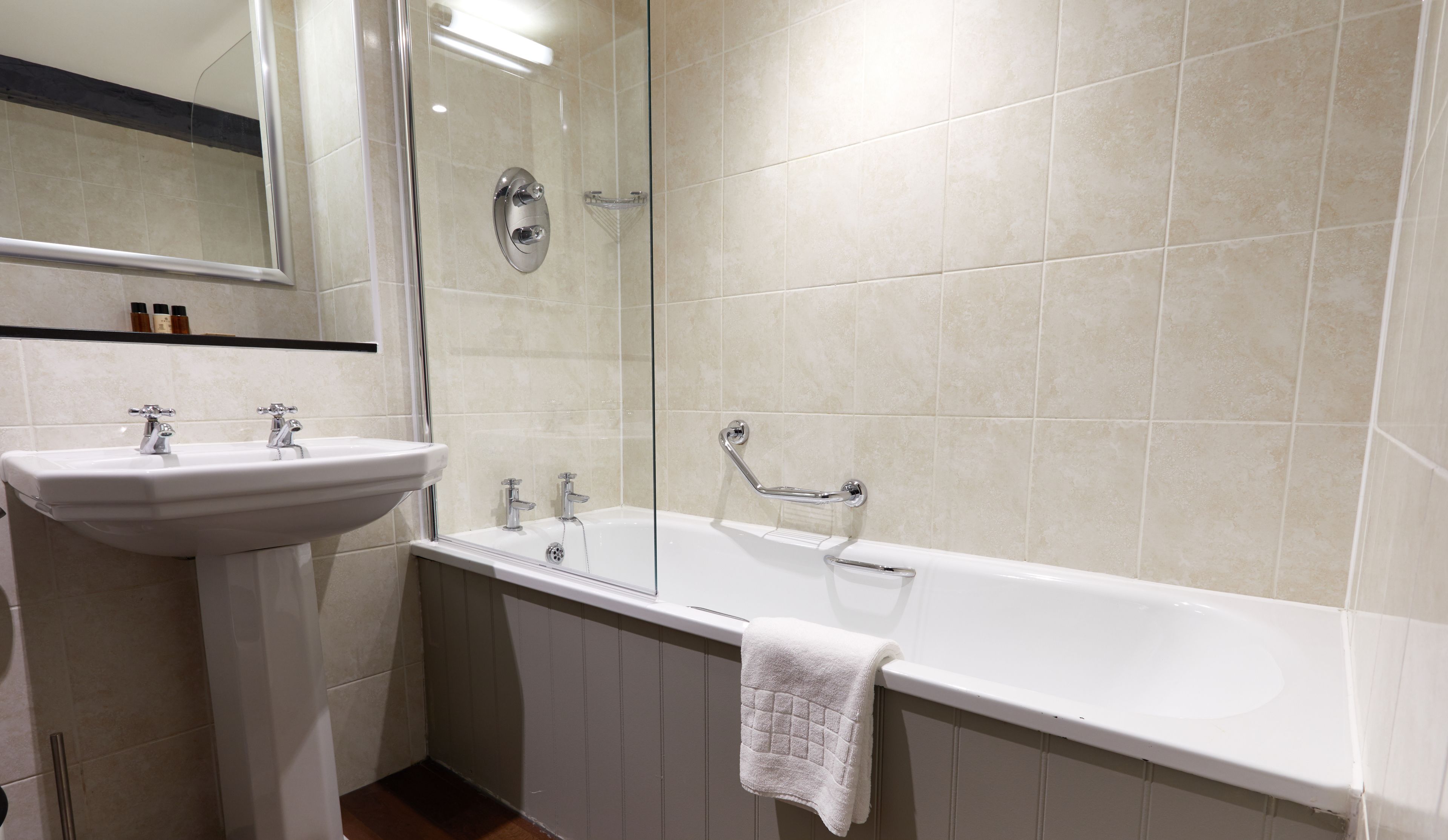 Un baño con lavamanos blanco, bañera y mampara de vidrio.