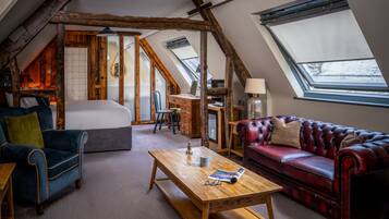 A loft-style room with a bed, a red leather sofa, a wooden coffee table, and a desk with a lamp.