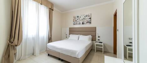 Un dormitorio con cama, cortinas, una mesita de noche y un cuadro en la pared.
