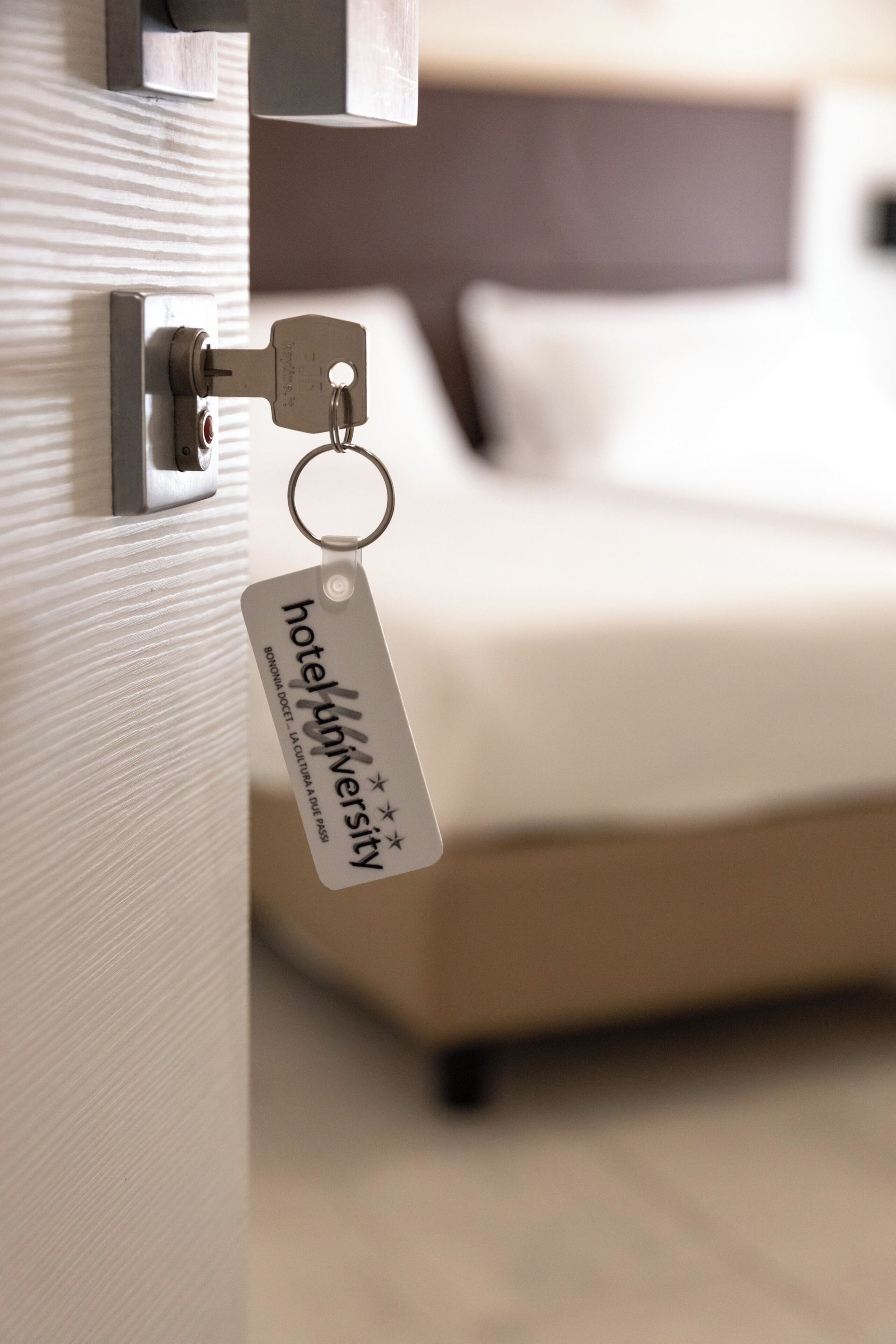 A hotel keychain with 'hoteluniversity' text, a bed, and a door lock.