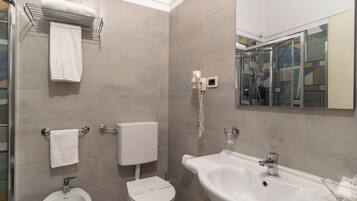 Une salle de bain moderne équipée d’un bidet, de toilettes, d’un lavabo et d’un miroir.