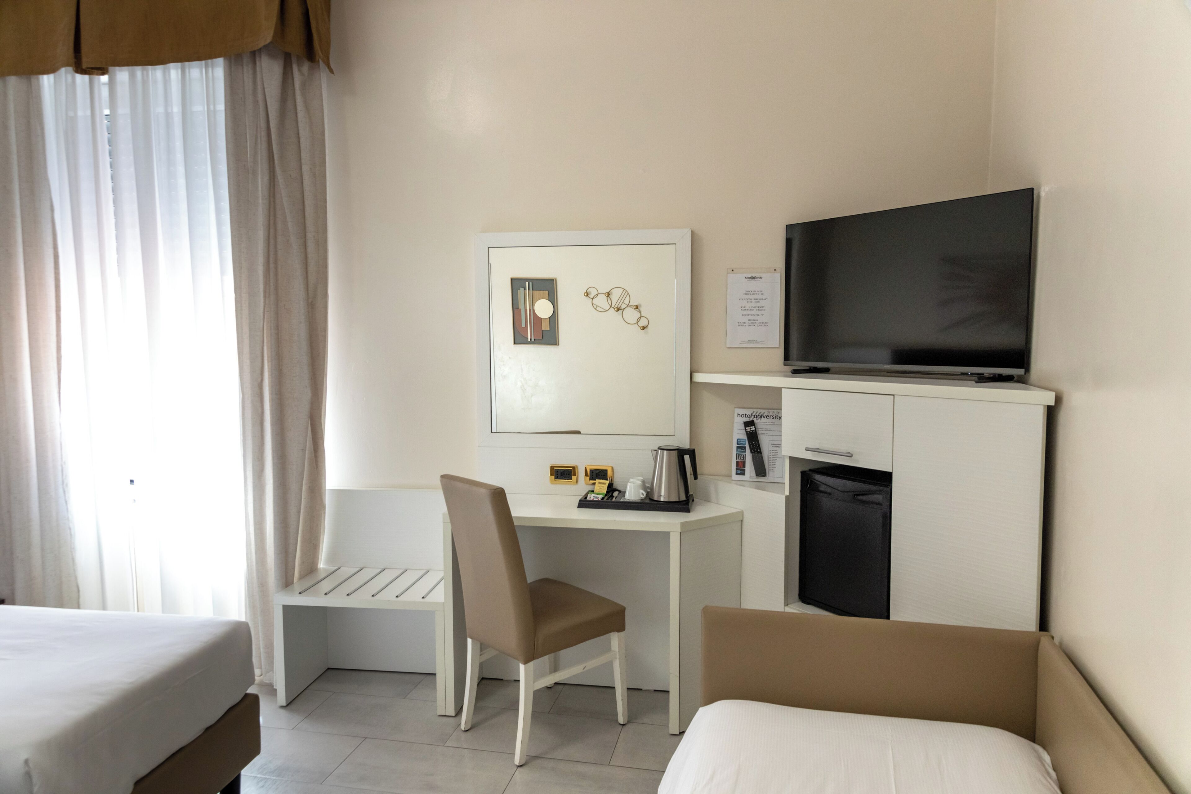 Una camera d'albergo con un letto, una scrivania con una sedia, una televisione e un angolo cottura.