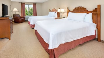 Ein Hotelzimmer mit zwei Betten, einem Fernseher, einem Schreibtisch und einem Sessel.