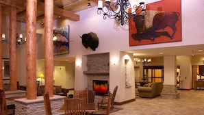A spacious lobby with a stone fireplace, wooden furniture, and a large buffalo mural.