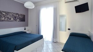 A bedroom with two beds, a flat-screen TV, an air conditioner, and a window with curtains. - Residence Progresso (Jesolo)