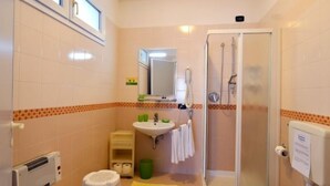 A small bathroom with a toilet, sink, and shower. - Residence Progresso (Jesolo)
