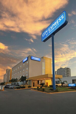 Un hotel City Express by Marriott con diseño moderno, varios pisos y estacionamiento.