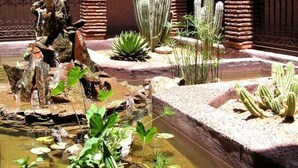 A courtyard with a water feature, cacti, and a stone wall. - Kasbah Le Mirage (Marrakech)