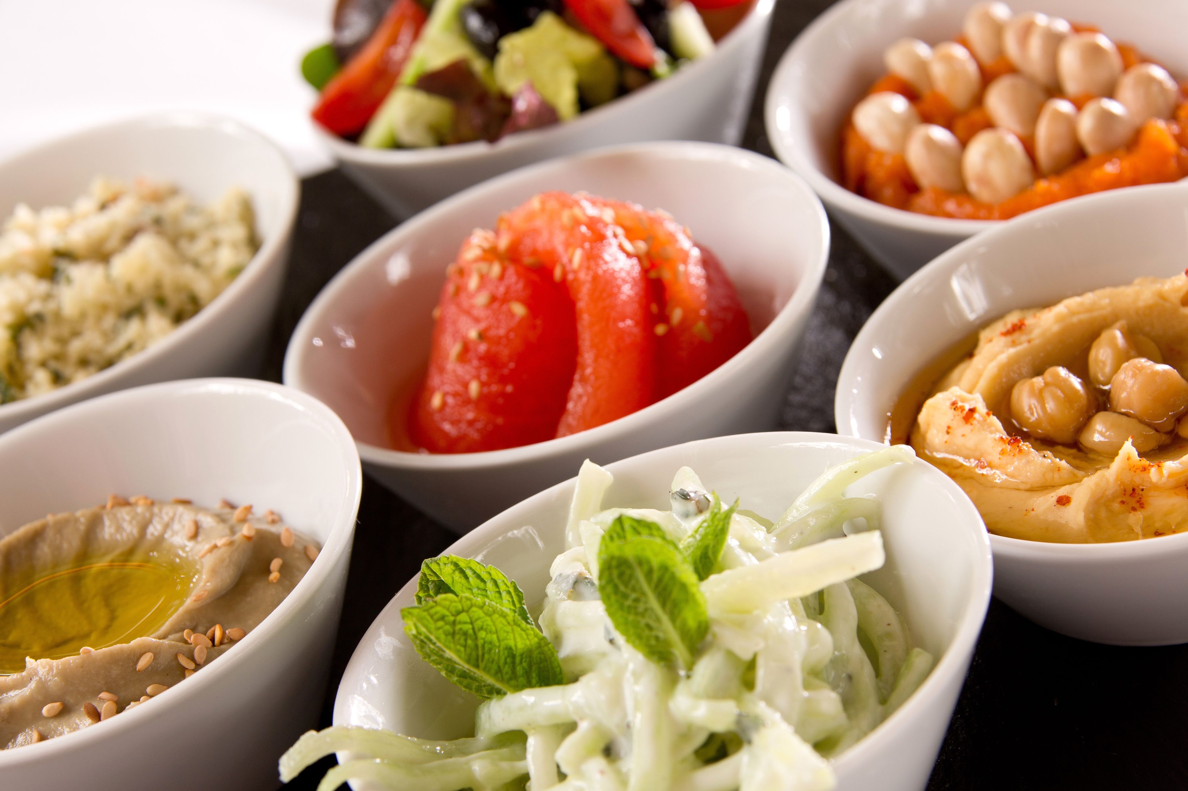 A variety of bowls containing different dips and salads.