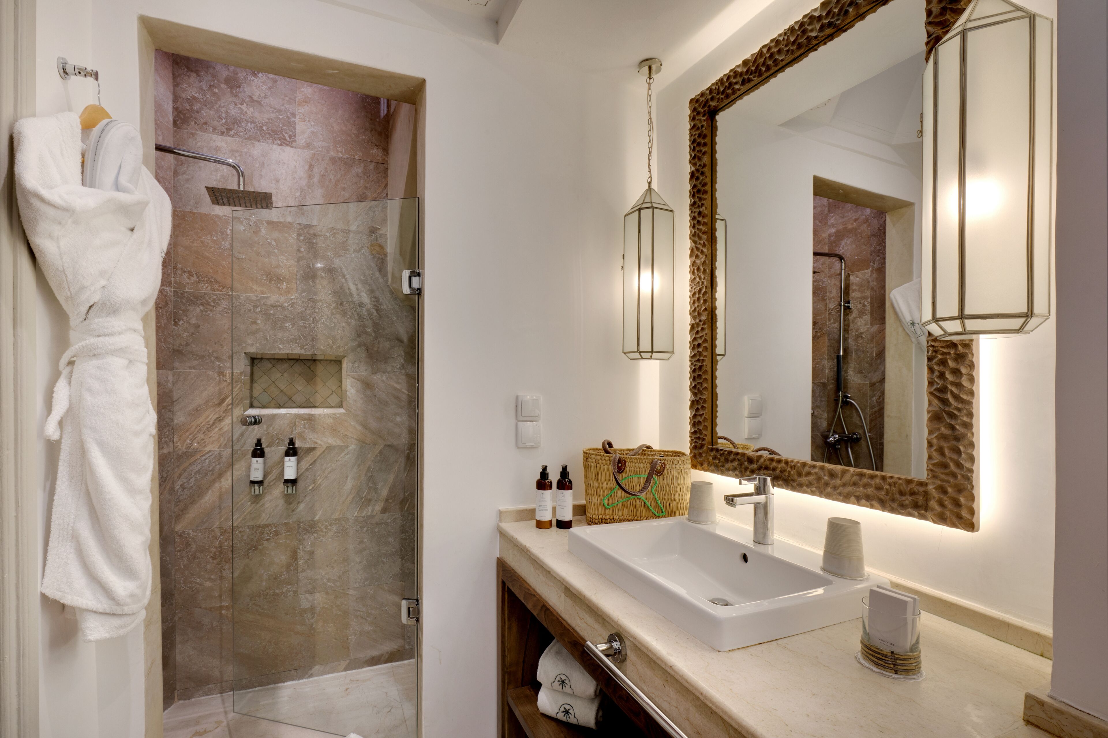 Un baño con ducha acristalada, un espejo grande y un tocador con lavabo y toallero.