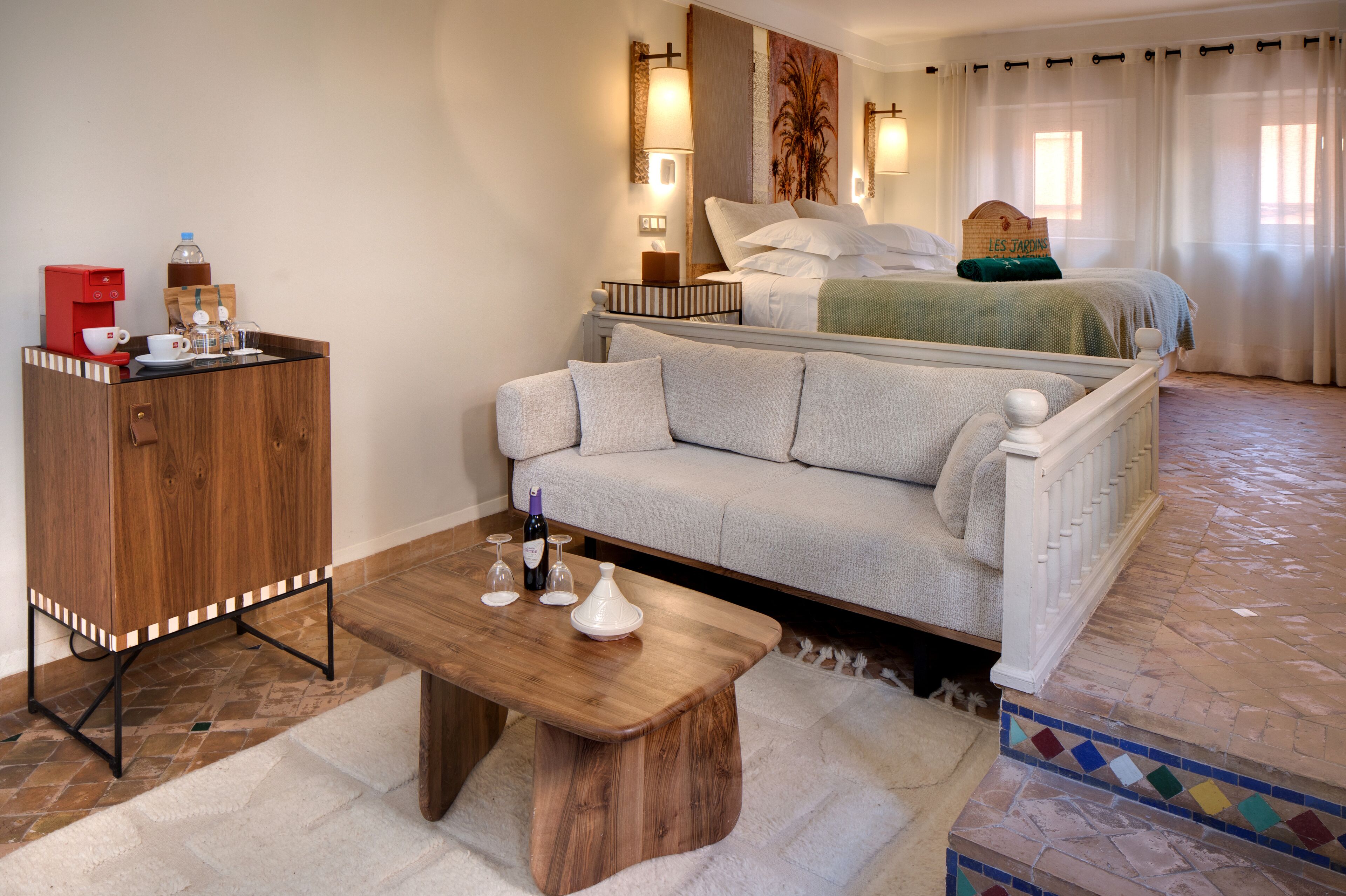 A hotel room with a bed, a sofa, a wooden cabinet, and a coffee station.