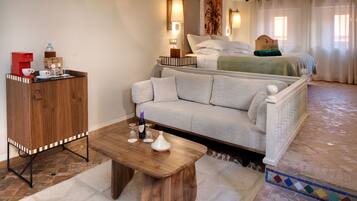 A hotel room with a bed, a sofa, a wooden cabinet, and a coffee station.