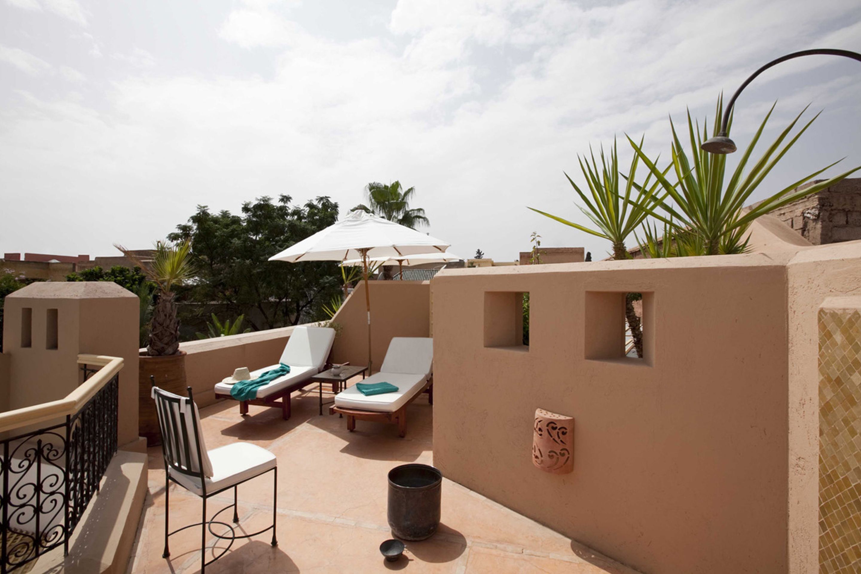 Una terraza en la azotea con sillones de descanso, una mesa y un muro decorativo.