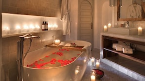 Un baño moderno con una bañera independiente, velas y una bata colgada en la pared.