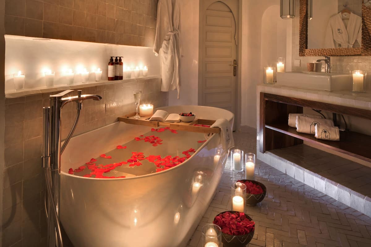 Un baño moderno con una bañera independiente, velas y una bata colgada en la pared.