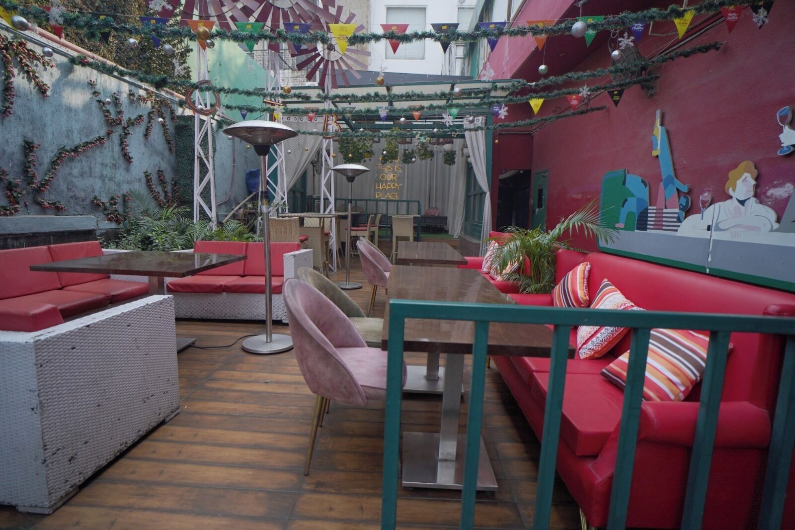 An outdoor seating area with red and white furniture, including sofas and chairs, and a mural on the wall.