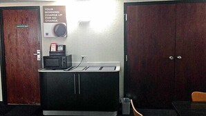 A kitchenette with a microwave, a coffee maker, and a sign about morning charge. - Motel 6 Omaha, NE (Omaha)