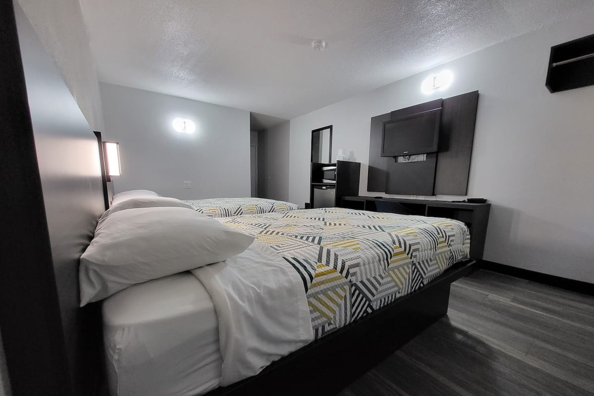 A modern hotel room with a large bed, a flat-screen TV, a desk, and a mirror.